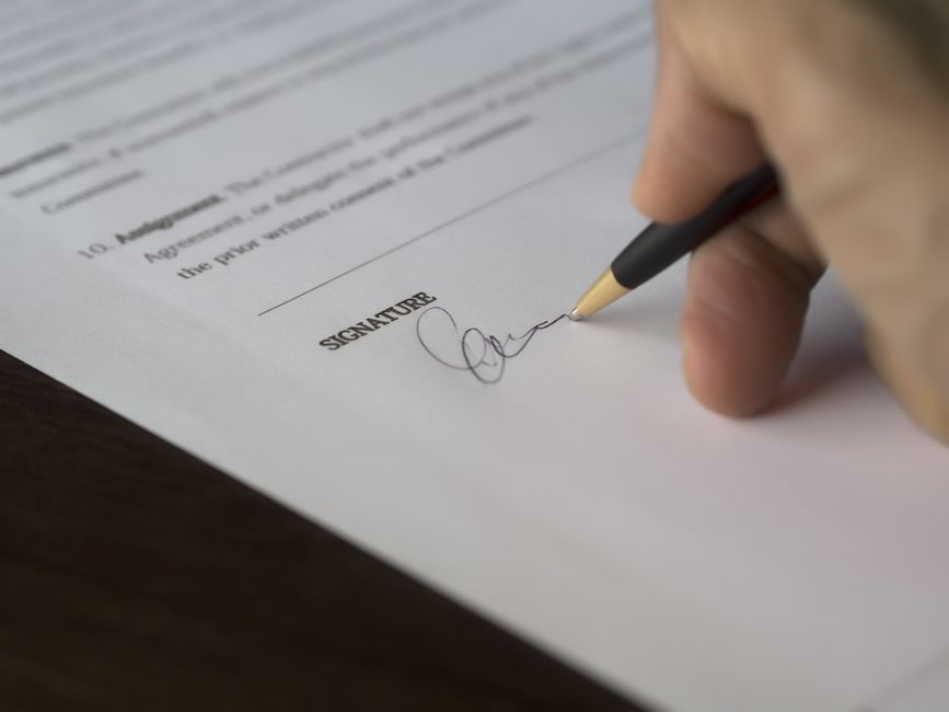 Signature d'un document juridique au stylo — la politique de cookies fait partie de la documentation juridique obligatoire d'un site web