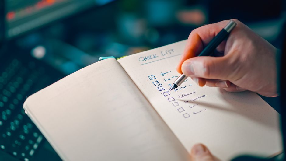 Une main rédigeant une checklist dans un carnet — la structure type d'une politique de cookies, étape par étape